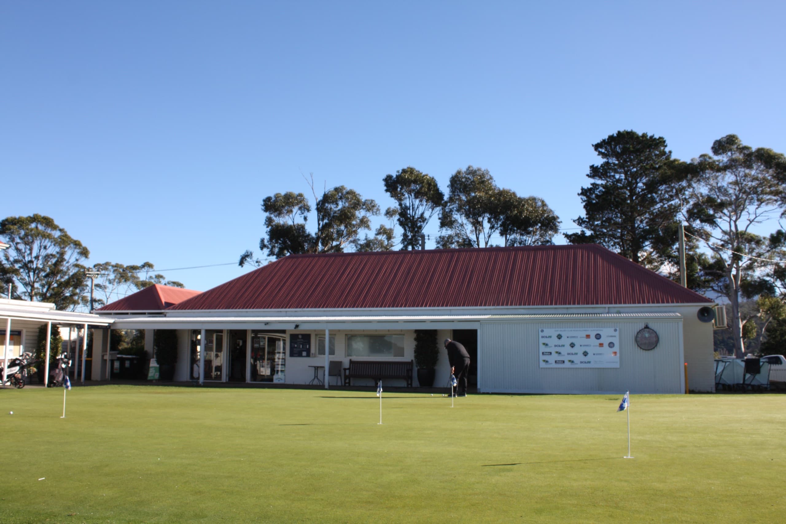 A golfer putting on the practice green beside the clubhouse